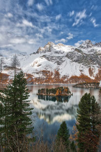 Scenic view of lake by snowcapped mountains against sky