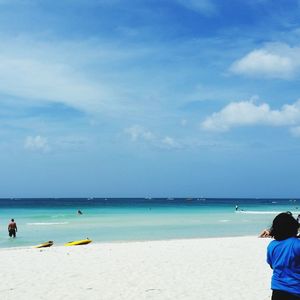 Rear view of people standing on beach against sky