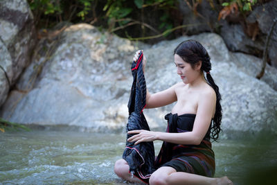 Young woman holding cloth on stream at forest