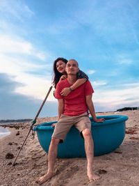 Smiling young couple on beach against sky