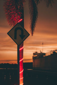 Low angle view of road sign against sky during sunset