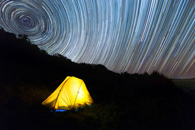 Illuminated tent on field against sky at night