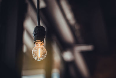 Low angle view of light bulb hanging on ceiling