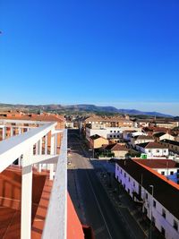 High angle view of road by buildings against clear blue sky