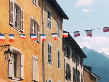 Low angle view of flags hanging on building against sky