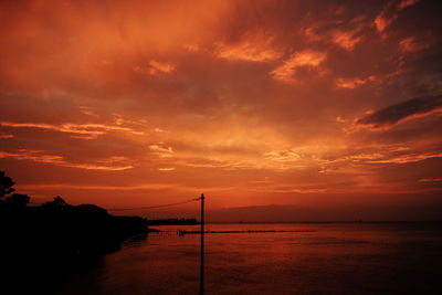 Scenic view of sea against dramatic sky during sunset