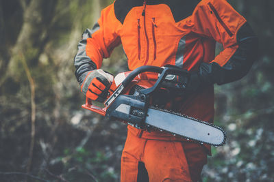 Man holding a chainsaw cut the  trees. lumberjack at work gardener working outdoors  in the forest. 