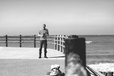 Rear view of woman standing by sea against clear sky