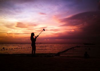 Silhouette of people on beach at sunset