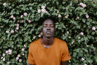 Portrait of young man standing against plants