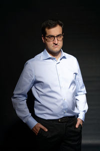 Young man wearing hat standing against black background