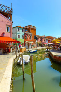 Boats in canal against clear blue sky