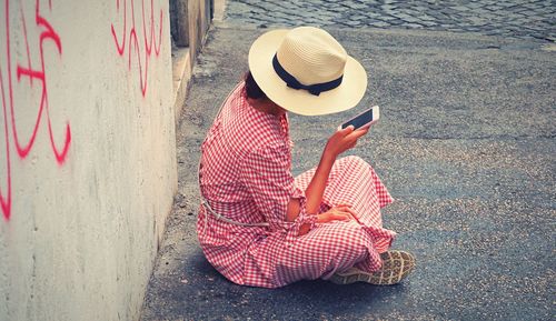 Rear view of woman wearing hat sitting outdoors