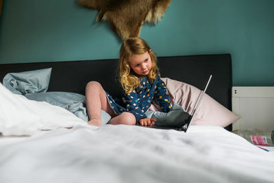 Midsection of woman sitting on bed at home