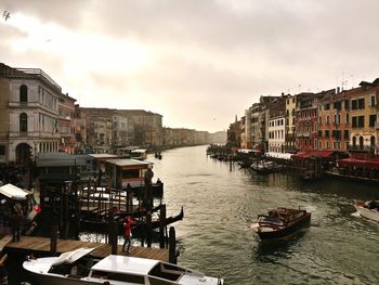 Boats moored in canal with city in background