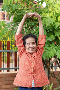 Portrait of active senior old woman warming stretching exercising isolated on nature background. 