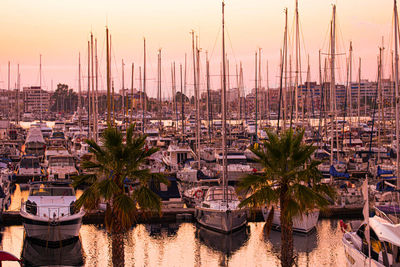 Sailboats moored in harbor at sunset