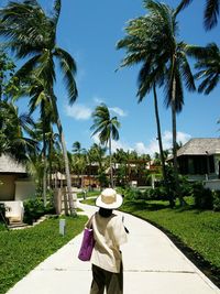 Rear view of woman with palm trees against sky