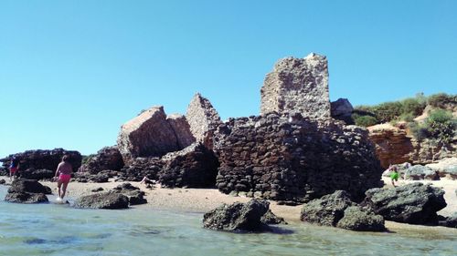 Man standing on rocks against clear blue sky