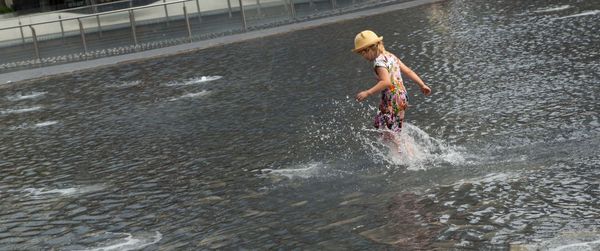 Full length of boy splashing water in river