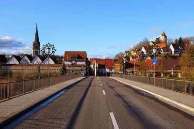 Road by buildings against sky in city