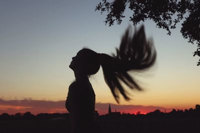 Silhouette woman standing against sky during sunset