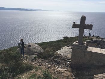 High angle view of woman standing by cross against sea