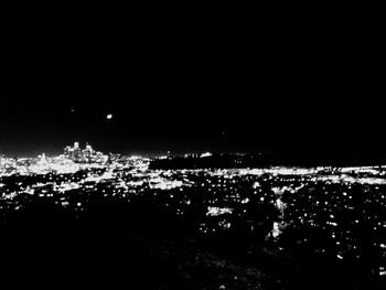 Illuminated city by sea at night