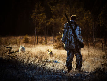 Rear view of man with gun standing on field