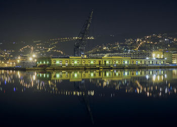 Illuminated harbor buildings against sky at night