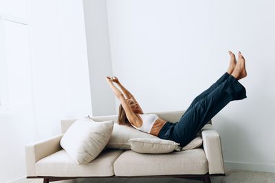 Low section of woman using laptop on sofa at home