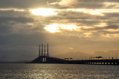 Bridge over sea against sky during sunset