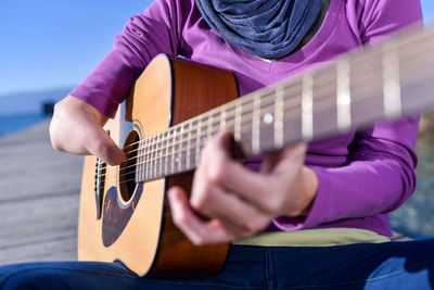 Midsection of man playing guitar