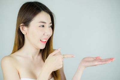 Portrait of young woman smiling against white background