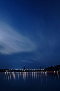 Silhouette wooden posts in sea against sky at night