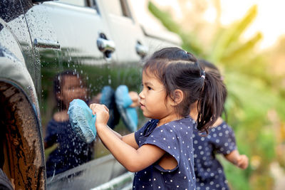 Side view of girl cleaning car
