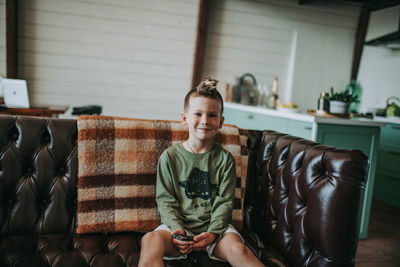 Portrait of smiling boy sitting on sofa