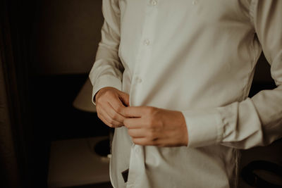 Midsection of man getting dressed while standing at home