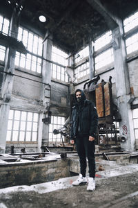 Full length portrait of young man standing in abandoned building