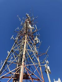 Low angle view of communications tower against clear blue sky