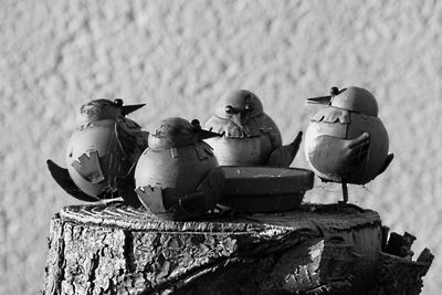 Close-up of bird figurines on tree stump