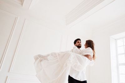 Bridegroom picking up bride in room during wedding ceremony