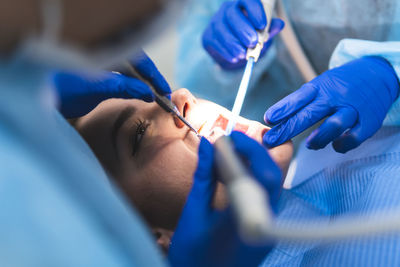 Young dentist with assistant examining patient in clinic