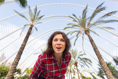Happy young woman with palm trees against plants