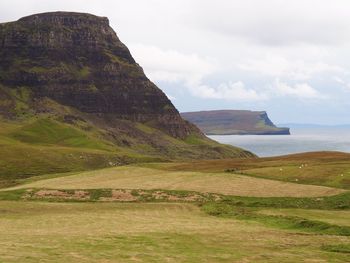 Scenic view of sea by mountains against sky