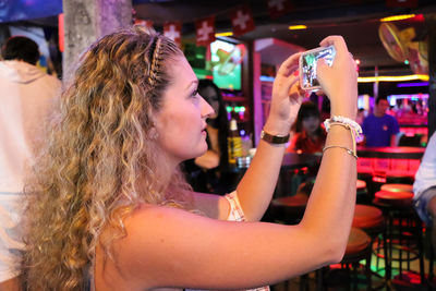 Side view of young woman with drink at night