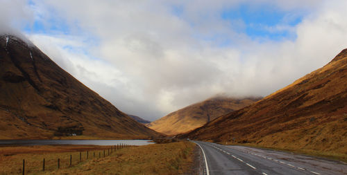 Country road against cloudy sky