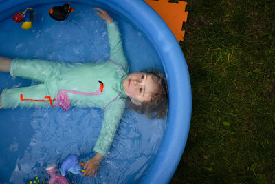 High angle view of girl lying in wading pool