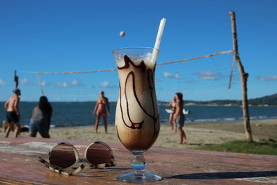 Close-up of people at beach against blue sky