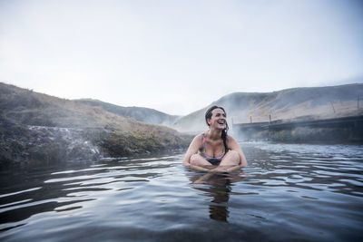 Pretty woman lying on back in thermal water river.